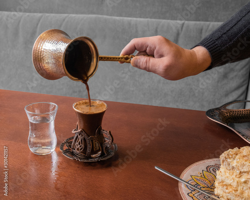 Fotografie strong aromatic turkish coffee is poured from turk in a beautiful glass