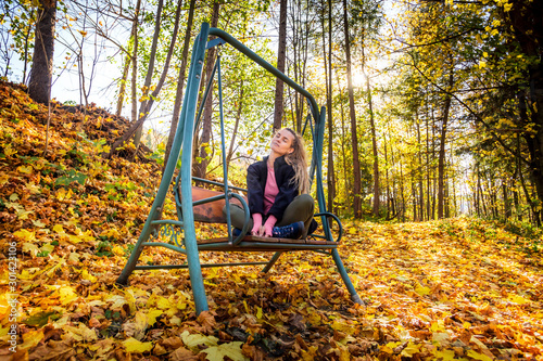 Young woman on swing in beautiful autumn forest