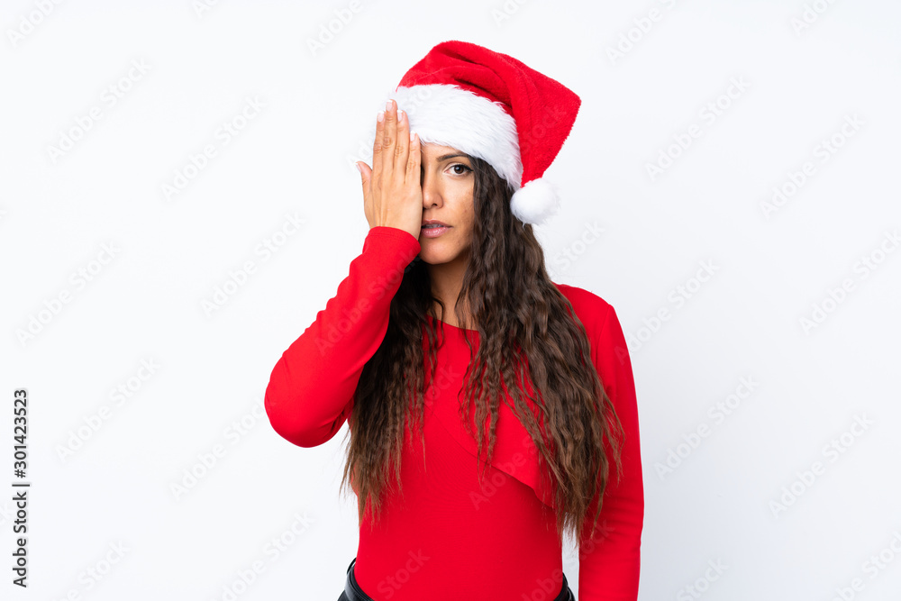 Girl with christmas hat over isolated white background covering a eye by hand Girl with christmas hat over isolated white background covering a eye by hand