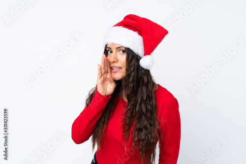 Girl with christmas hat over isolated white background whispering something