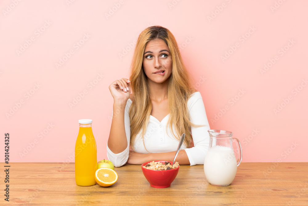 Young blonde woman having breakfast milk having doubts and with confuse face expression Young blonde woman having breakfast milk having doubts and with confuse face expression