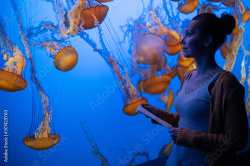 Woman watching exotic jellyfishes in an aquarium