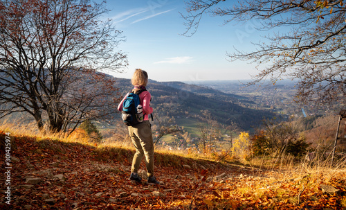 Hiker young woman with backpack rises to the mountain top on mountains landscape background