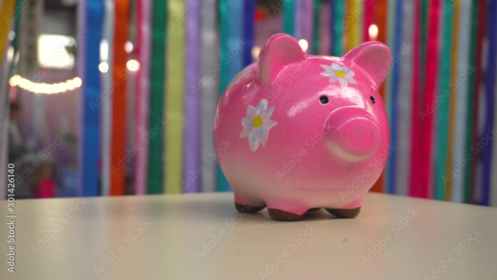 Pink porcelain pig moneybox with flowers standing on desk Pink porcelain pig moneybox with flowers standing on desk