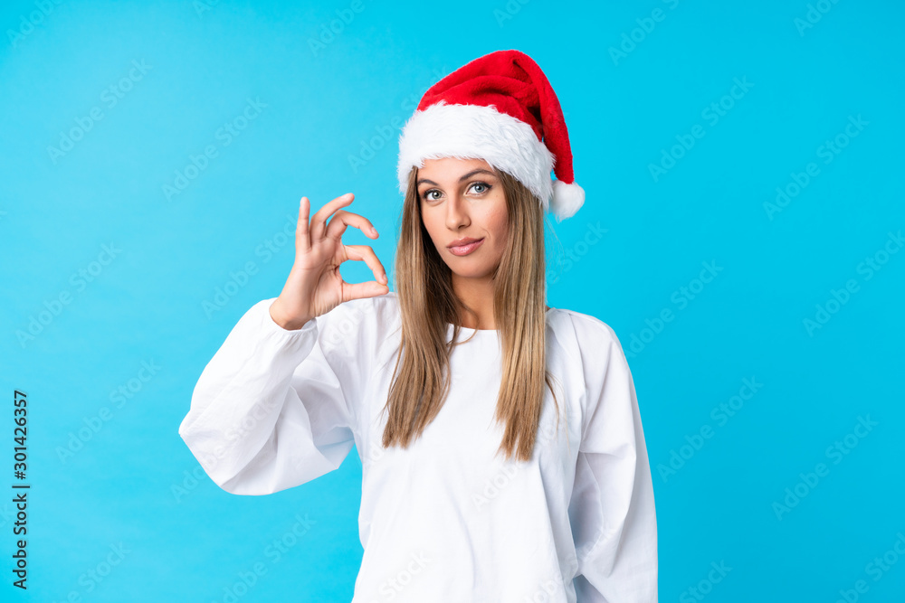 Girl with christmas hat over isolated background showing an ok sign with fingers Girl with christmas hat over isolated background showing an ok sign with fingers