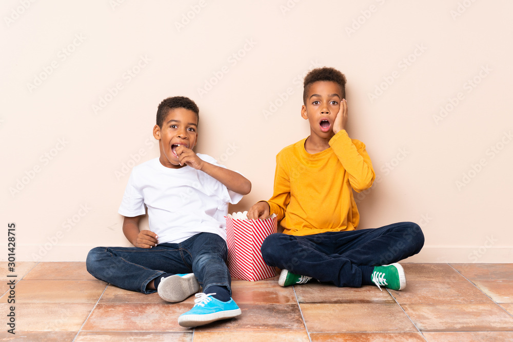 African American brothers holding popcorns and doing surprise gesture African American brothers holding popcorns and doing surprise gesture