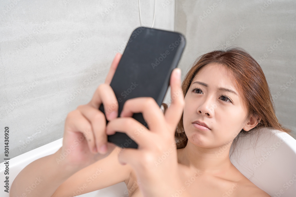 Young and beautiful girl using phone relaxing in the retro bath indoors Young and beautiful girl using phone relaxing in the retro bath indoors