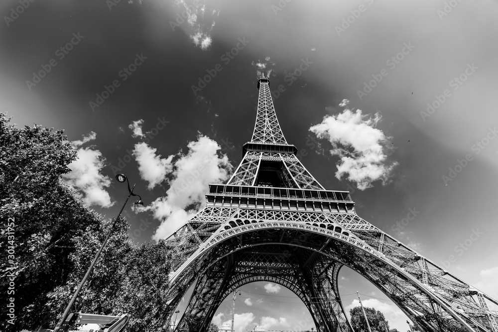 World famous Eiffel tower under a blue sky with clouds in black and white