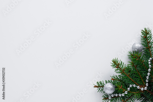 Beautiful christmas arrangement with festive decorations such as spruce tree branches, silver chain and little shiny baubles. All on white background with copy space for wishes.