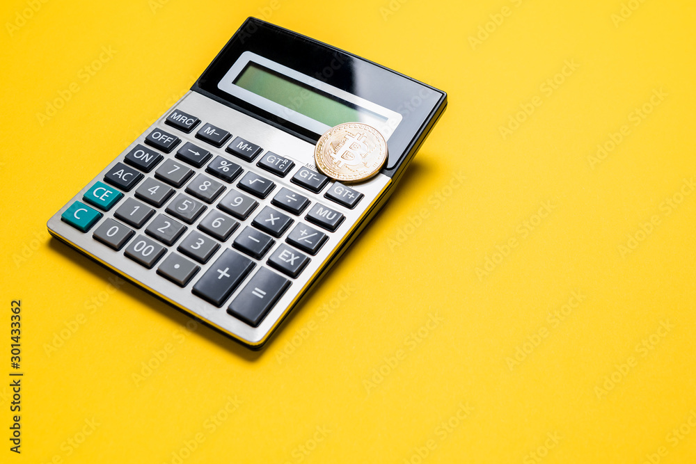 golden bitcoin coin on calculator close up isolated on yellow background golden bitcoin coin on calculator close up isolated on yellow background