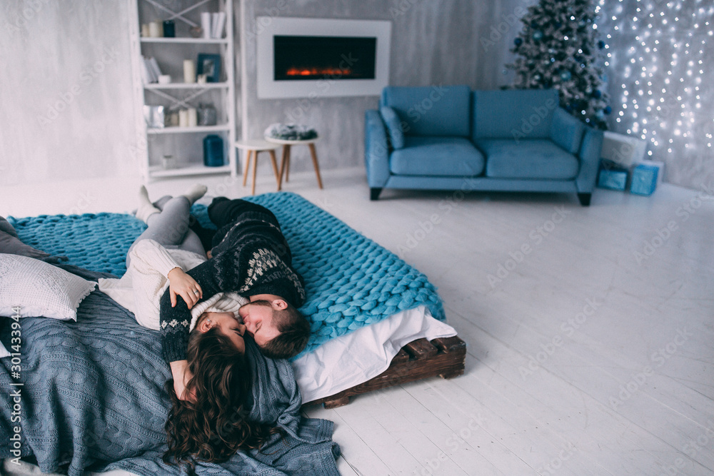 Obraz premium A guy with a girl is celebrating Christmas. A loving couple enjoys each other on New Year's Eve in a cozy home environment. New Year's love story.