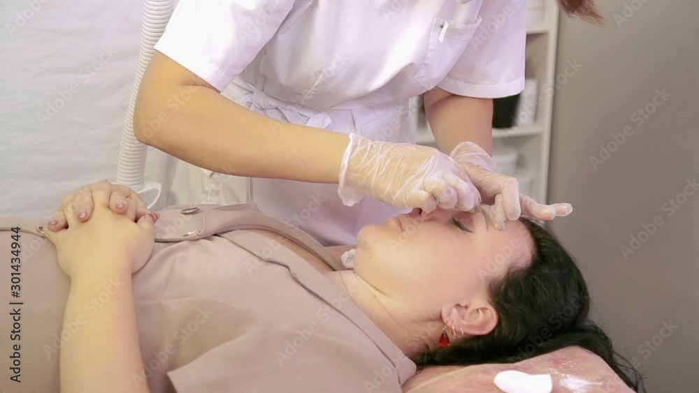 The beautician makes the correction of the eyebrows of the client sugar paste. The average plan The beautician makes the correction of the eyebrows of the client sugar paste. The average plan