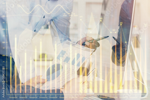 Double exposure of chart with businessman typing on computer in office on background. Concept of hard work.