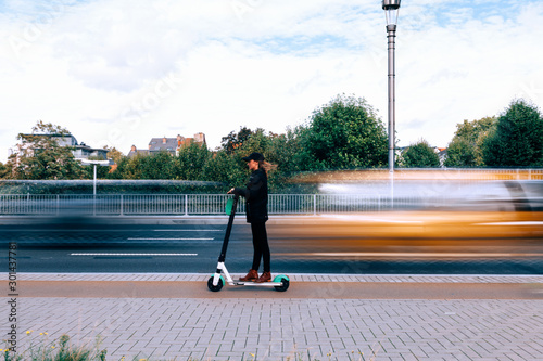 a woman drives safely an e scooter on a fast lane along a busy city street. Green mobility and new urban mobility concept photo