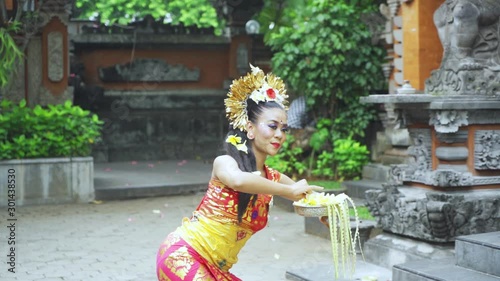 Slow motion of pendet dancer holding frangipani flower and dancing in the temple while wearing traditional costume photo