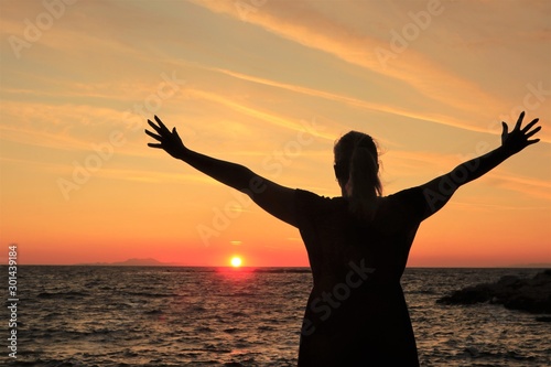 silhouette of a woman with open arms raised at sunset © Lars Gieger