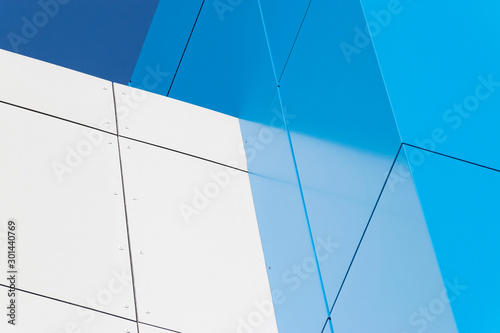 Geometric colored building facade elements with planes, lines and corners with light flare and reflections for an abstract background and texture of white, blue, gray colors. Place for text