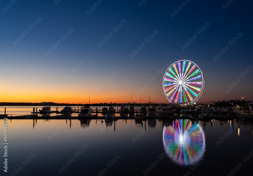 Illuminated ferris wheel at National Harbor near the nation capital of Washington DC at sunset - obrazy, fototapety, plakaty 