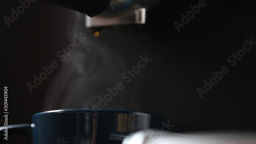Espresso coffee cup closeup steaming with espresso coffee machine , strong coffee cup aroma on dark background