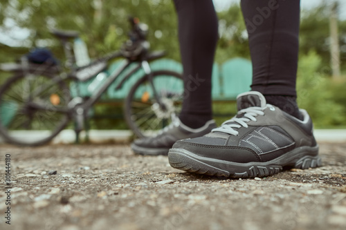 Close-up of the legs of a man in sneakers on the background of a bicycle
