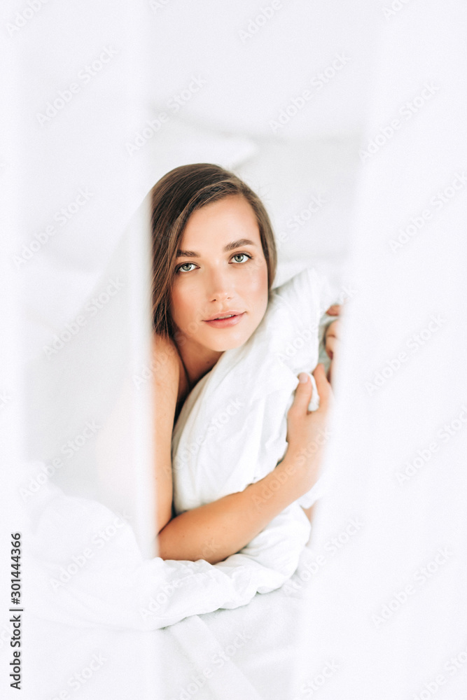 A young beautiful woman with long hair wakes up on the white bed at home, A young beautiful woman with long hair wakes up on the white bed at home,