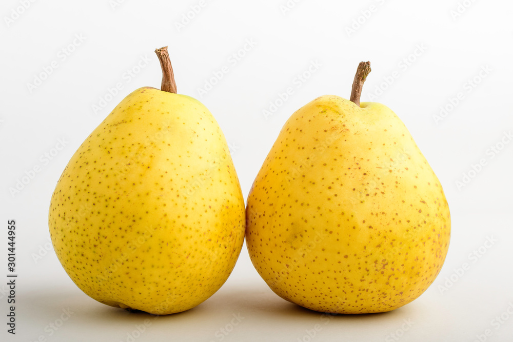 Two fresh organic ripe yellow pears on table, isolated on white background, side view with soft focus of tasty healthy food Two fresh organic ripe yellow pears on table, isolated on white background, side view with soft focus of tasty healthy food
