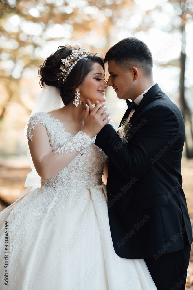 Bridal couple holding each other just after the wedding ceremony. Portrait of happy newly wed couple with head to head standing in garden. Autumn wedding