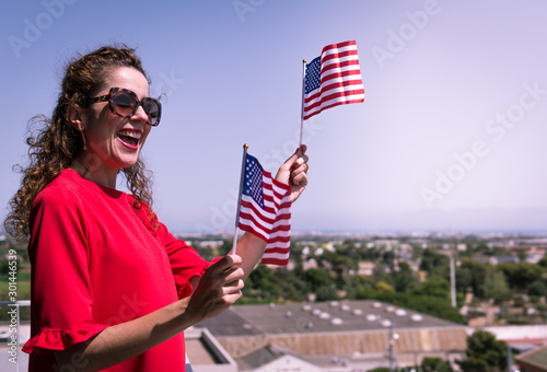 Red dressed woman with USA national flag hand celebrating a patriotic and american national holiday like 4ht of July, Flag day, national day or memorial day. photo