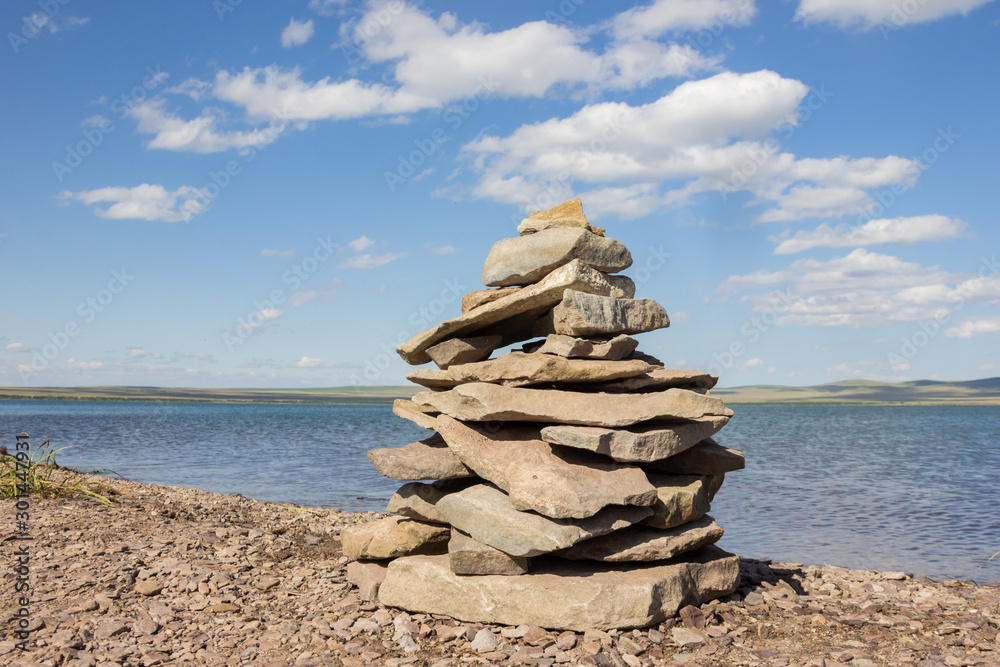Balance stones pyramid meditation harmony similar with blue lake and sky on background Balance stones pyramid meditation harmony similar with blue lake and sky on background