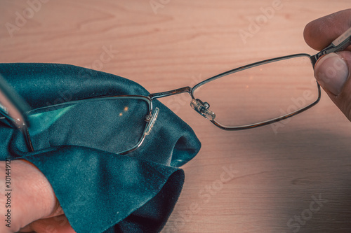 Cleaning glasses. A man wipes his glasses with a cloth. Storage and care for glasses. Selective focus