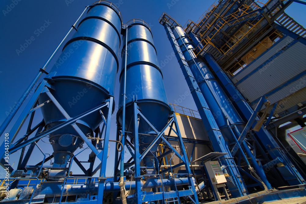 Equipment for production of asphalt, cement and concrete. Concrete plant. High tower of an asphalt plant. Harmful production. A mixture of bitumen and gravel, a mix machine. Equipment for production of asphalt, cement and concrete. Concrete plant. High tower of an asphalt plant. Harmful production. A mixture of bitumen and gravel, a mix machine.
