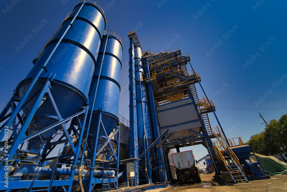 Equipment for production of asphalt, cement and concrete. Concrete plant. High tower of an asphalt plant. Harmful production. A mixture of bitumen and gravel, a mix machine. Equipment for production of asphalt, cement and concrete. Concrete plant. High tower of an asphalt plant. Harmful production. A mixture of bitumen and gravel, a mix machine.