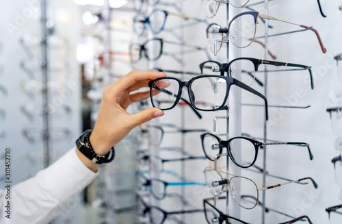Row of glasses at an opticians. Eyeglasses shop. Stand with glasses in the store of optics. Woman chooses spectacles. Eyesight correction. photo