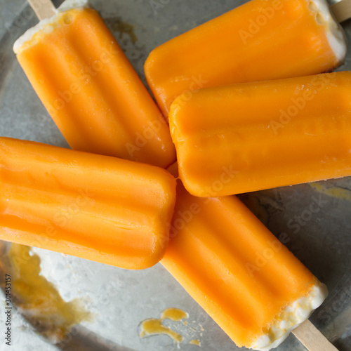 Several orange ice cream bars on a galvanized tray. 