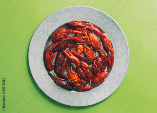 Several boiled crayfish or crawfish on a galvanized steel platter on a bright green background. Overhead view with copy space.  photo