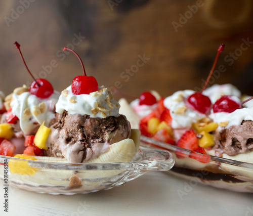 Two banana splits topped with whipped cream and cherries.  photo