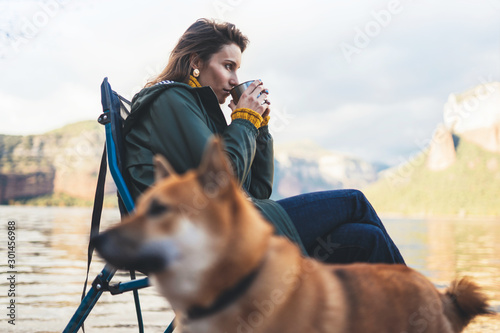 tourist traveler girl relax drink tea together dog on background mountain, puppy pet woman rest on lake shore nature trip, friendship concept © A_B_C
