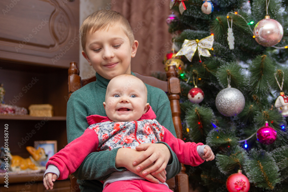 little girl laughs with boy at Christmas,happy little girl with her brother at home near Christmas tree for Christmas