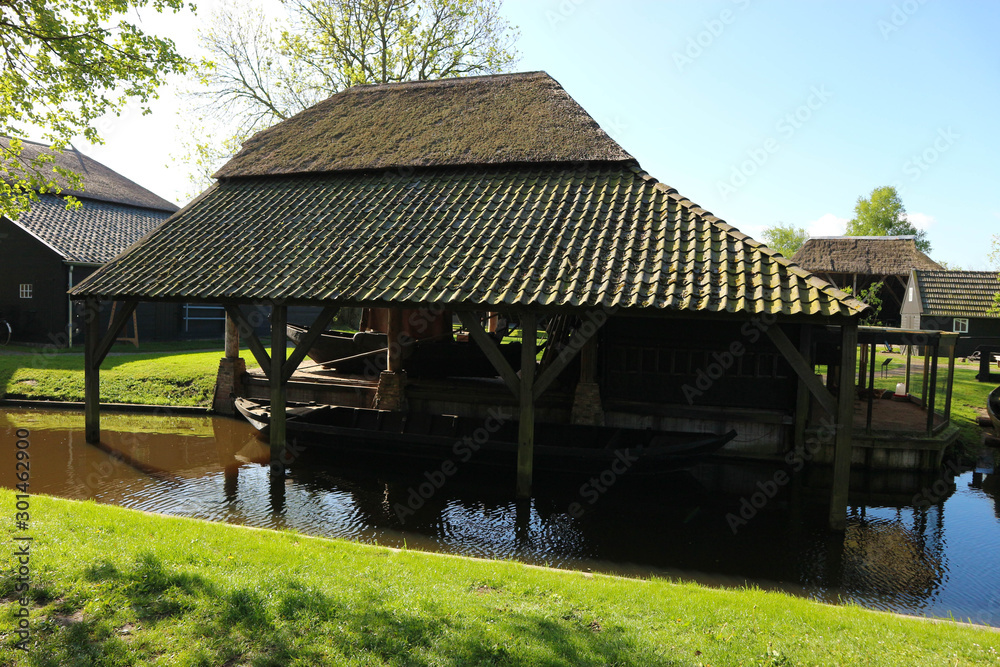 Dutch old wooden house with the parking place of a boat in the canal, Netherlands Dutch old wooden house with the parking place of a boat in the canal, Netherlands