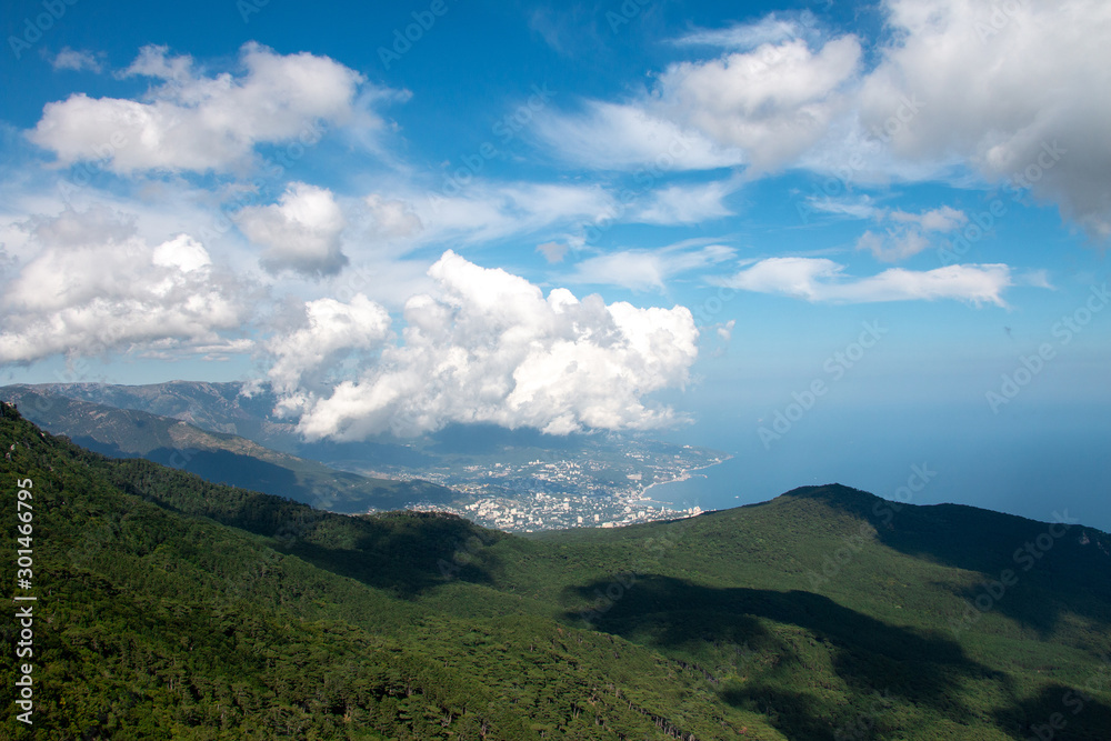Beautiful view of the coastal city from the mountains under the clouds. Green Forest. Travel photo.