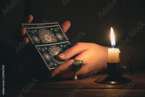 Fortune teller reading a future by tarot cards in the light of candle concept.
