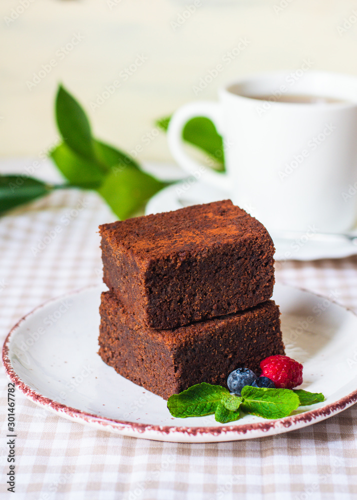 dark chocolate brownie pieces decorated with mint and berries on a white plate classical recipe dark chocolate brownie pieces decorated with mint and berries on a white plate classical recipe
