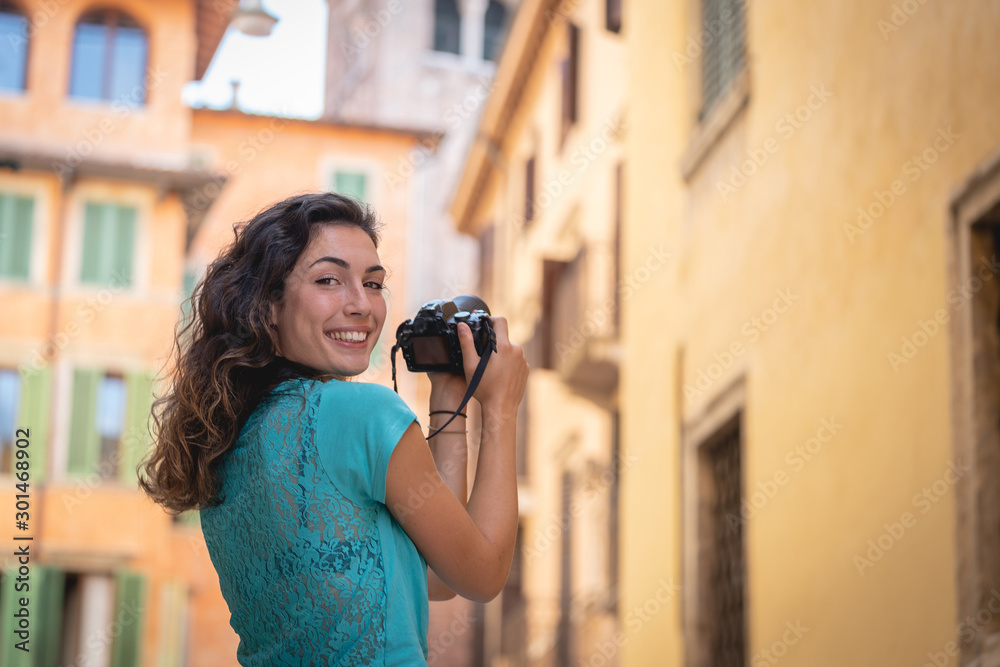 Tourist girl on vacation in Verona photographing a typical Italian street
