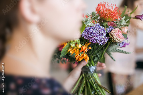 A girl holds a bouquet of different colored flowers in her hand. Florist training workshop on creating flower bouquets. Floristics Studio.