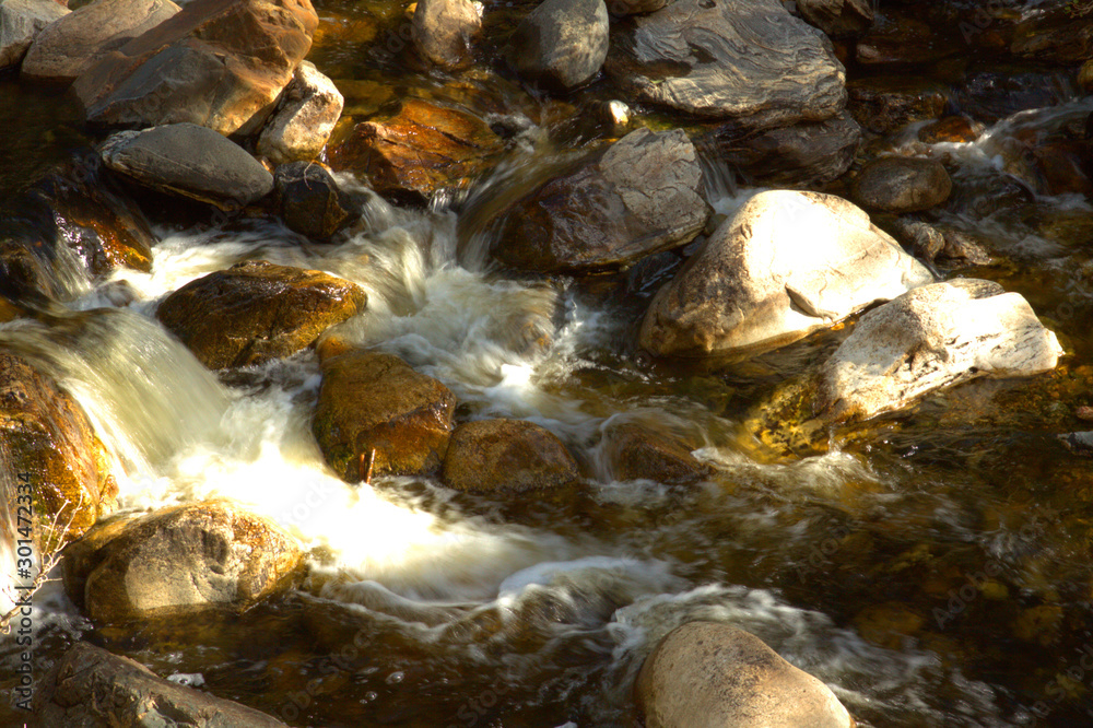 Water rushing across stones in rocky riverbed of crystal clear mountain stream. Water rushing across stones in rocky riverbed of crystal clear mountain stream.