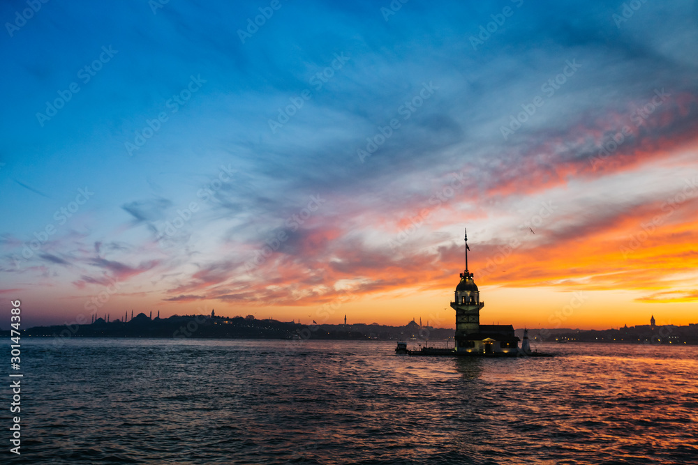 Fiery sunset over Bosphorus with famous Maiden's Tower (Kiz Kulesi) also known as Leander's Tower, symbol of Istanbul, Turkey. Scenic travel background for wallpaper or guide book