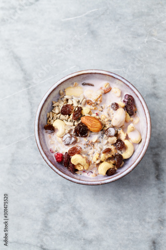 Bowl of granola with yogurt, nuts, raisins, cranberries and chia seeds. Concept for a tasty and healthy meal. Stone background. Top view. Copy space.