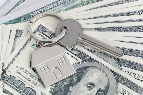 Home keys and a small house on currencies dollar background. The concept of renting or selling a house or flat, mortgage, investment or real estate, property buying. Money for the housing plan