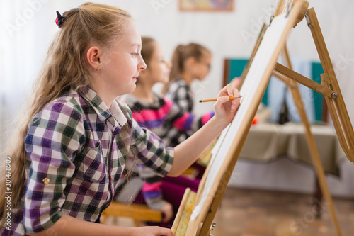 children draw on an easel in art school.