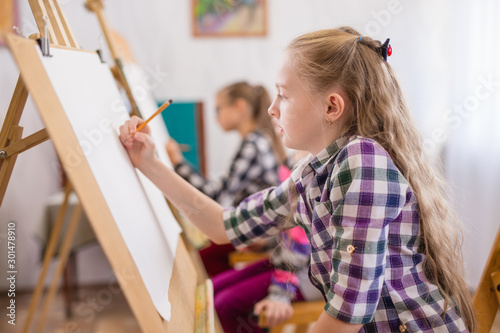 children draw on an easel in art school.